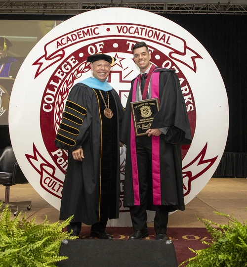 Two men standing on stage with award.